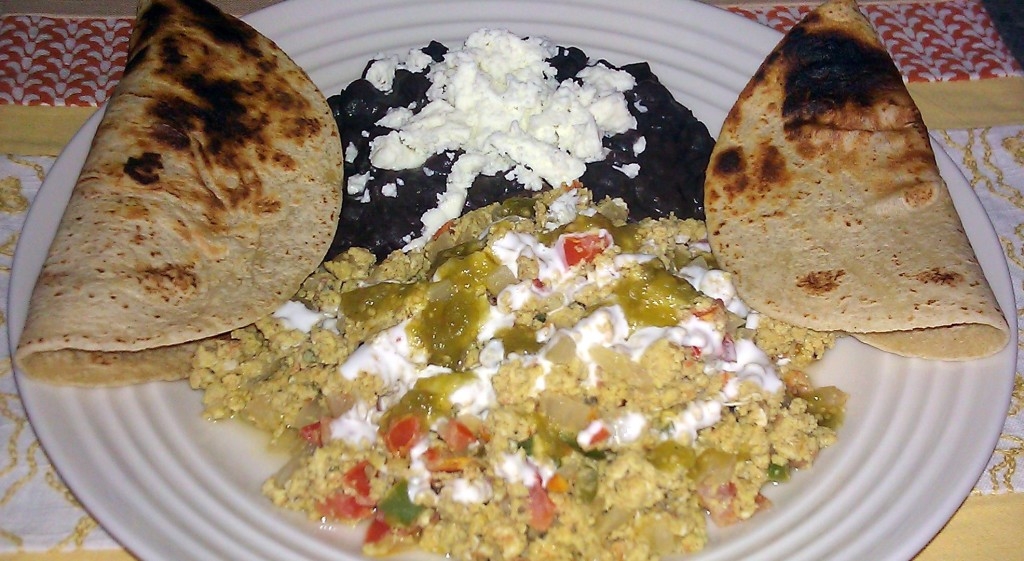 Scrambled eggs with salsa accompanied with refried beans and tortillas