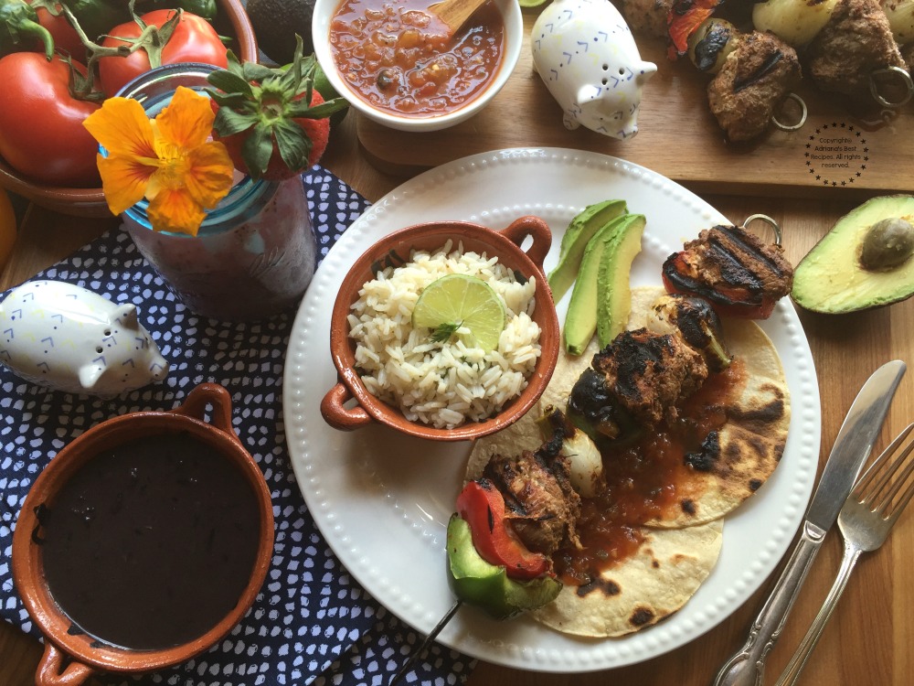 Serve the Chipotle Pork Loin Alambres with cilantro lime rice, black beans, avocado slices, tortillas and salsa