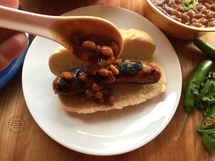 Smothering the grilled chicken dogs with sweet and spicy beans