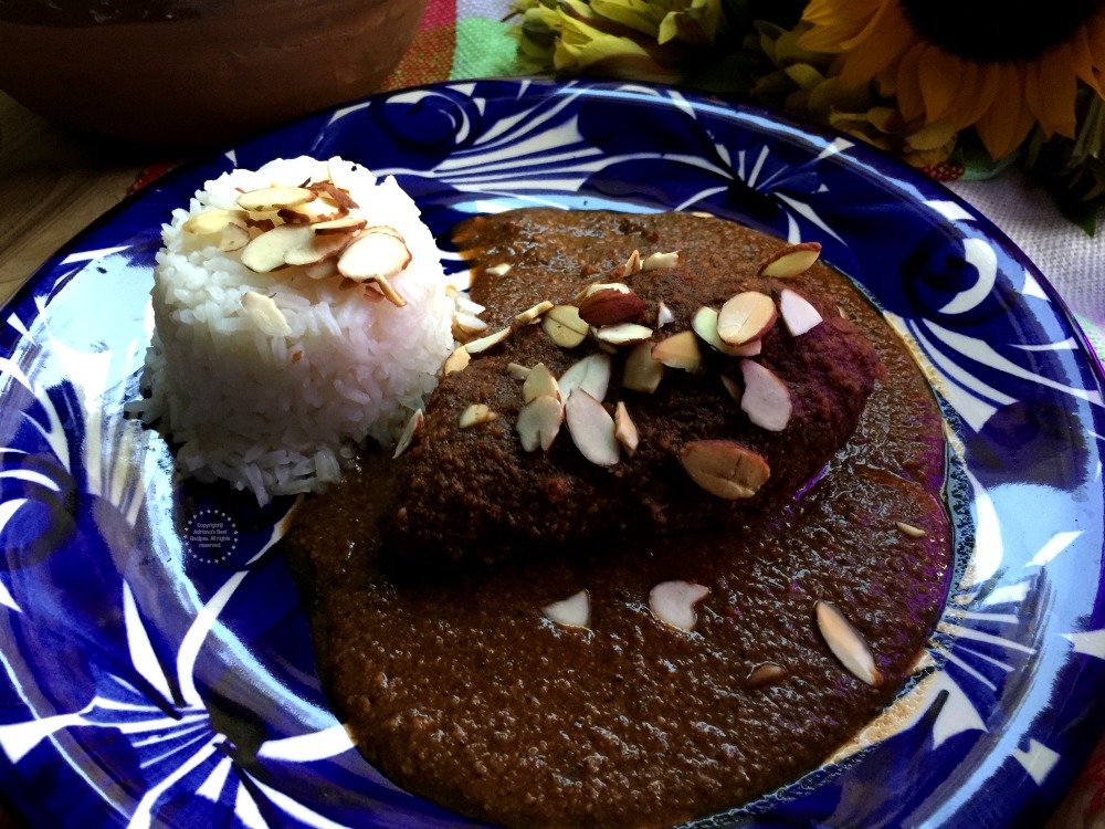 Serving the almond mole over chicken and with a side of rice