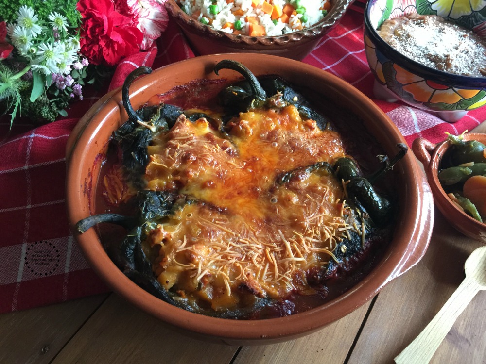 Sirviendo los chiles rellenos de picadillo de pavo acompañados de arroz blanco estilo mexicano y frijoles refritos bayos