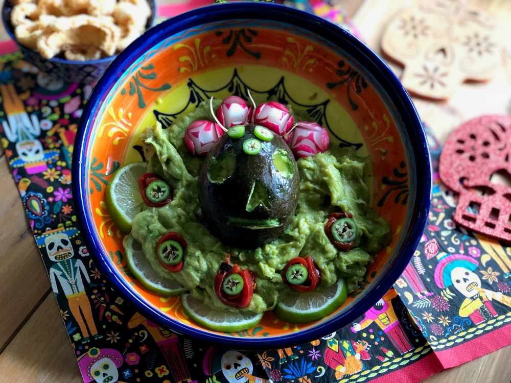A bowl of guacamole and an avocado carving