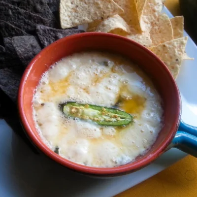 The recipe for the queso fundido has shredded cheese, and poblano peppers. Serving with corn chips for a tasty appetizer.
