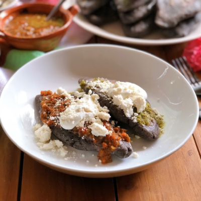 These are the blue corn tlacoyos served with green and red salsa, cream, and crumbled Mexican cheese