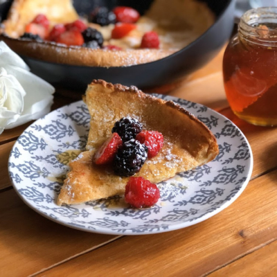 Dutch baby pancakes garnished with berries, honey, and confectioners sugar.