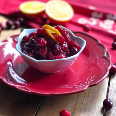 A bowl of spicy mustard cranberry sauce garnished with orange peel