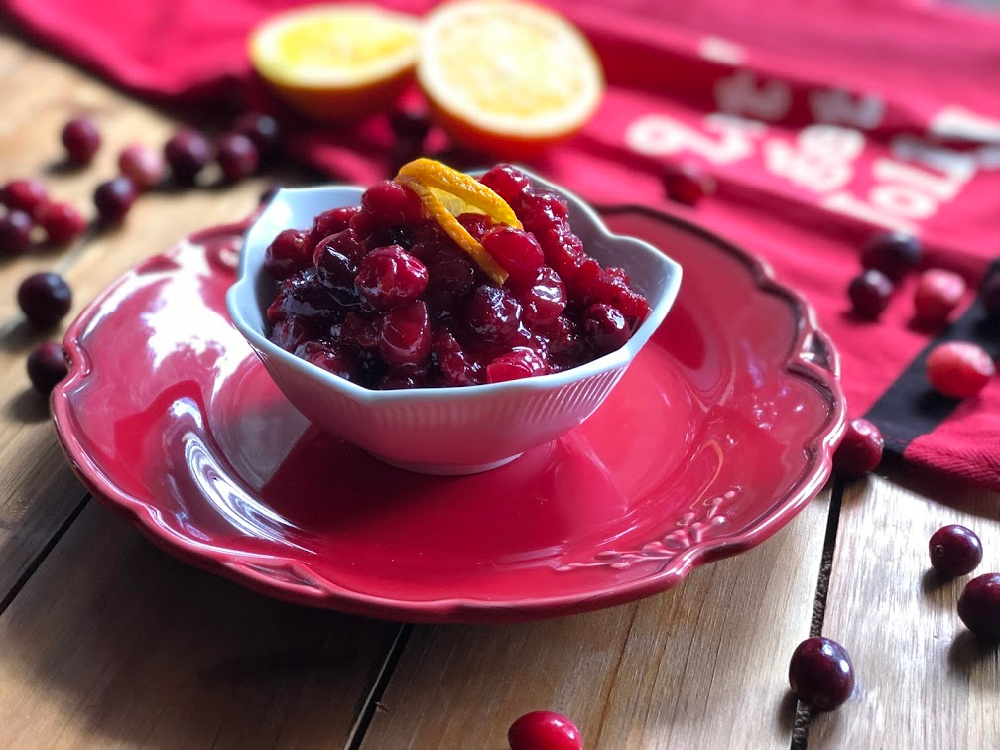 A bowl of spicy mustard cranberry sauce garnished with orange peel