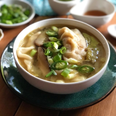 The chicken potstickers soup served on a bowl with green onions and serrano pepper slices