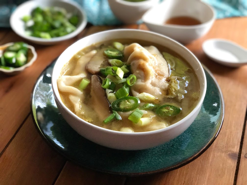 The chicken potstickers soup served on a bowl with green onions and serrano pepper slices