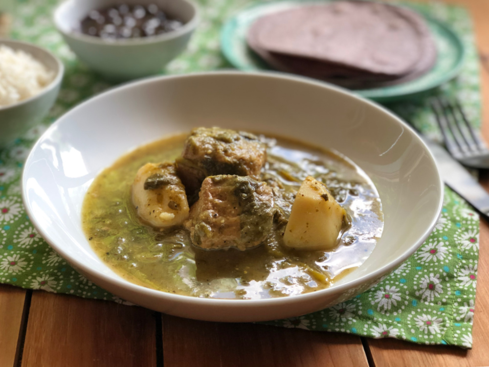 Un tazón blanco con cerdo con verdolaga en salsa de tomatillo