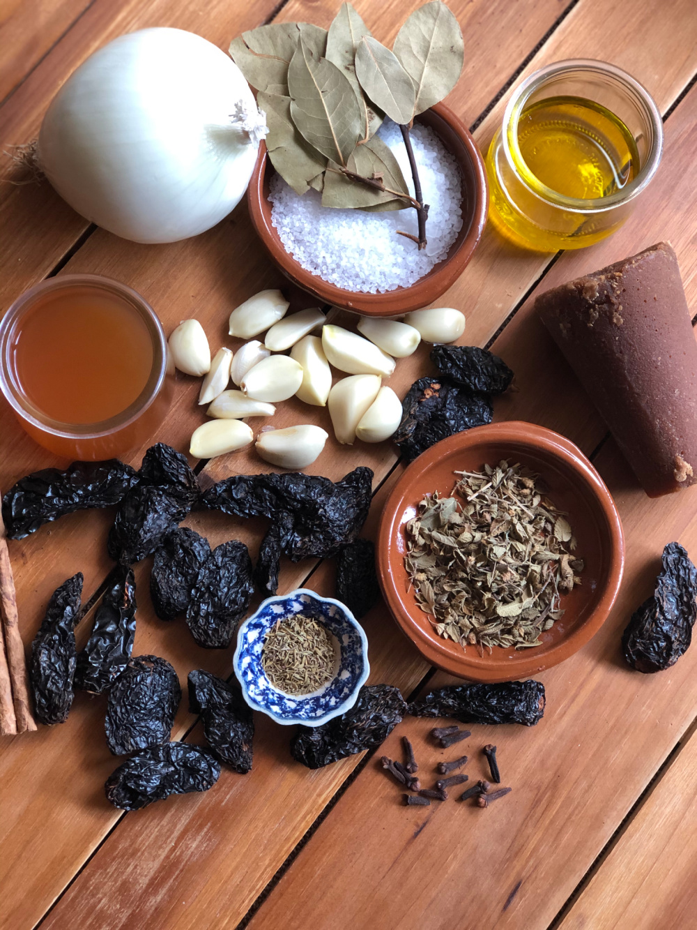 A top shot showing dried smoked chipotles, spices, vinegar, and produce