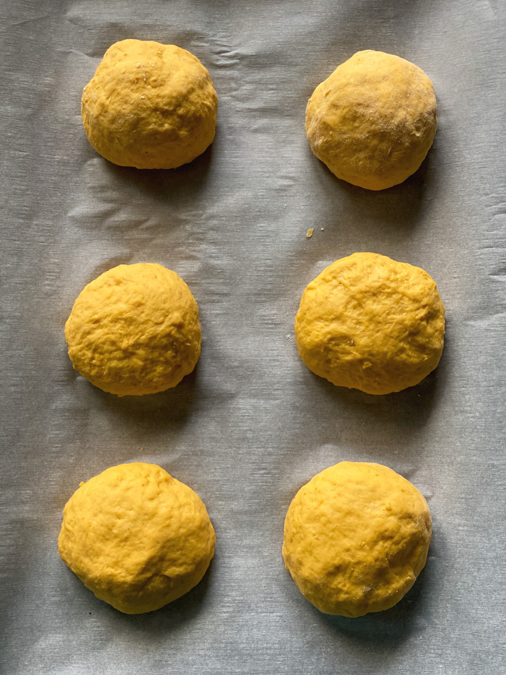 Bolas de masa descansando sobre una bandeja para hornear