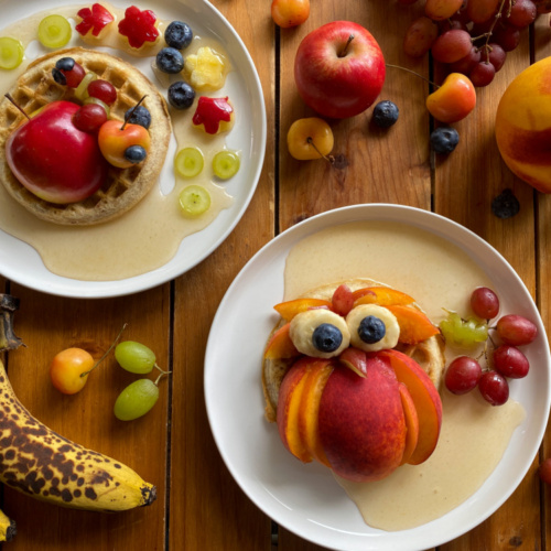 Dos platos servidos con frutas y waffles haciendo un diseño otoñal comestible