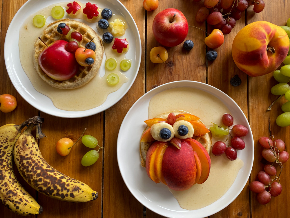 Dos platos servidos con frutas y waffles haciendo un diseño otoñal comestible