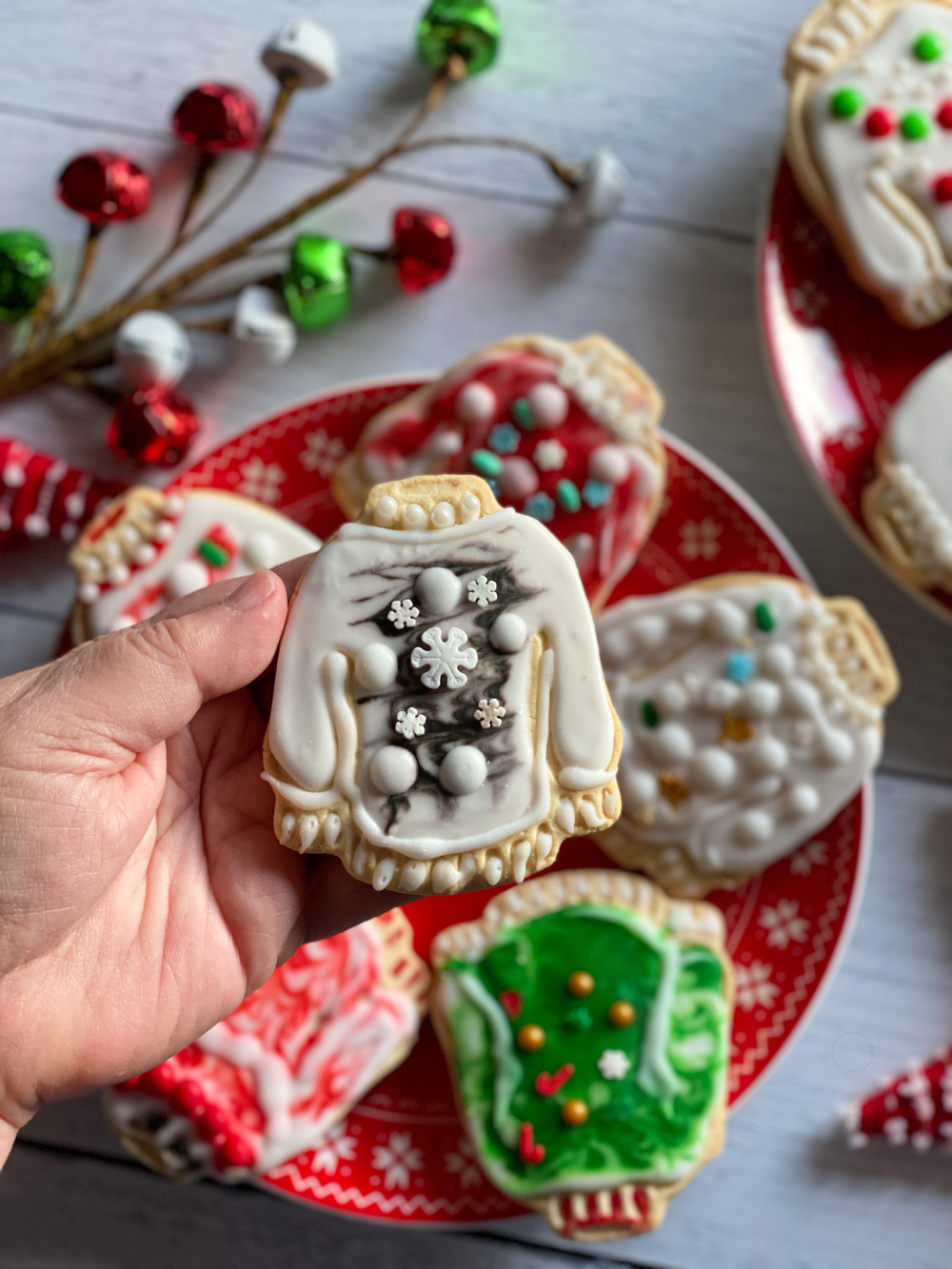 A hand holding a sugar cookie with holiday decorations