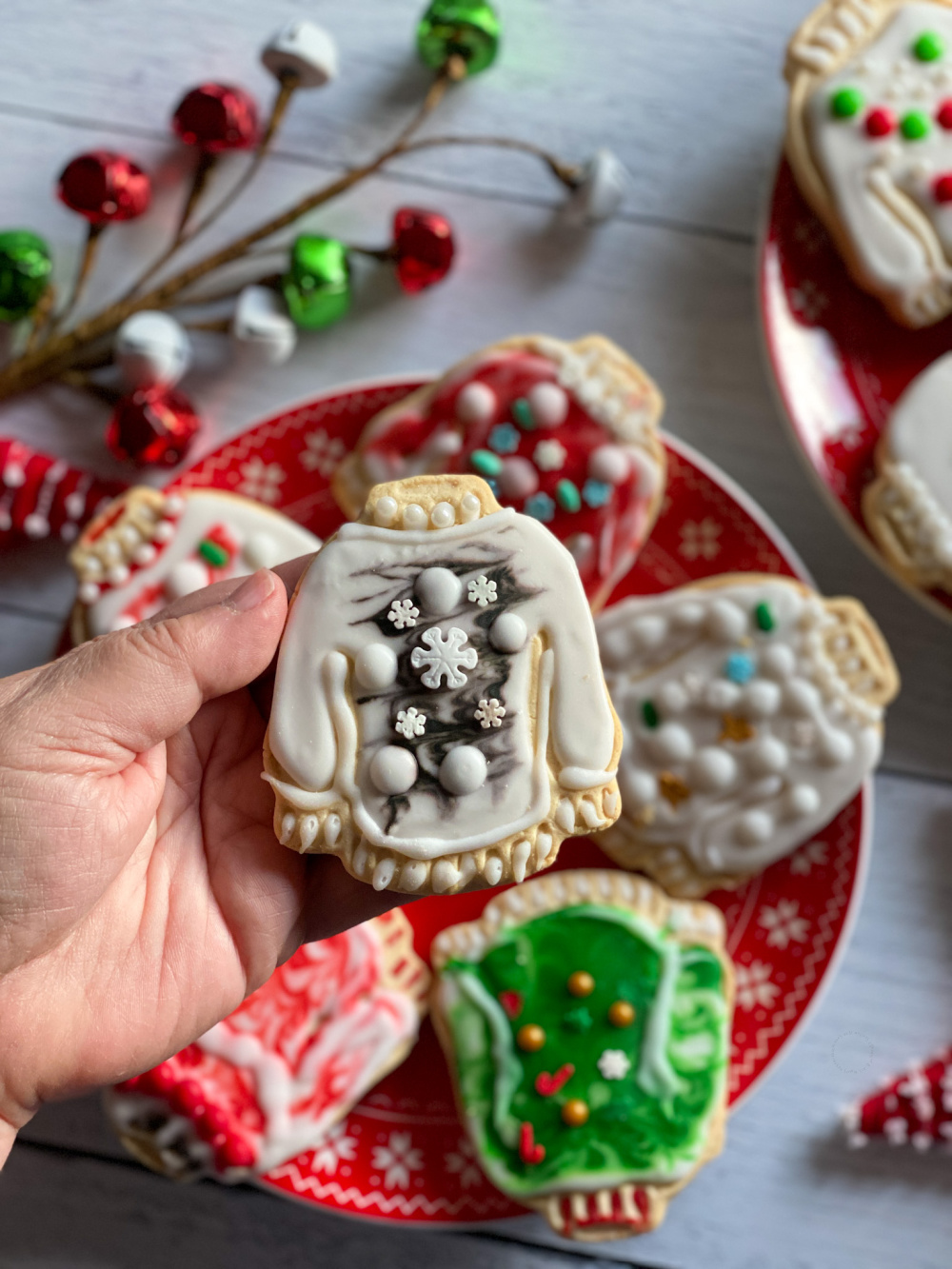 Una mano sosteniendo una galleta de azúcar con diseño de Suéteres Feos