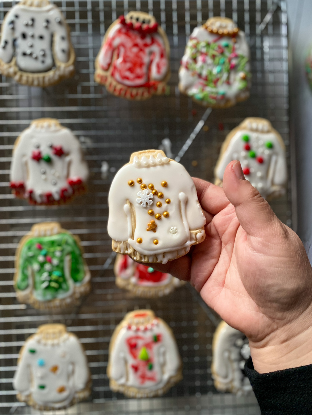 A hand holding an ugly sweater cookie design