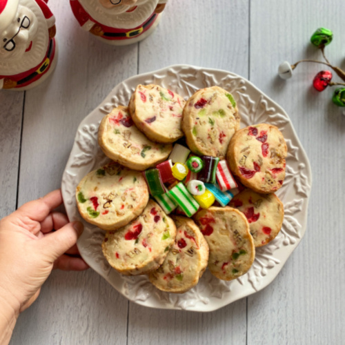 A hand placing a plate of jeweled icebox cookies in table