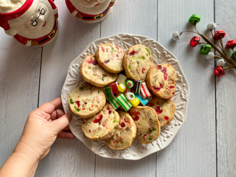 A hand placing a plate of jeweled icebox cookies in table