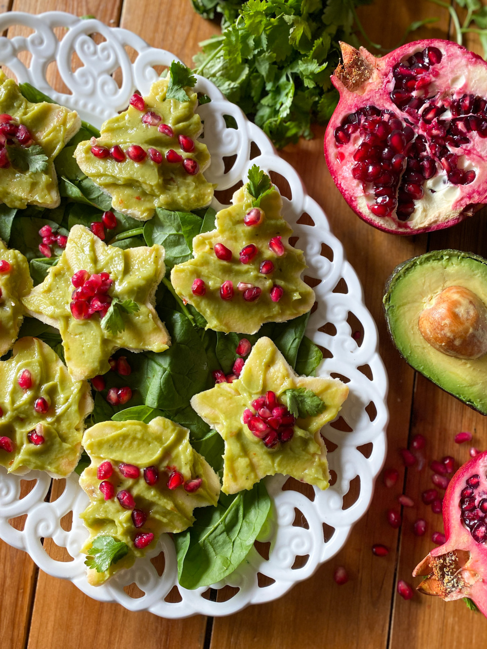 A tray of avocado toast appetizers topped with pomegranate seeds. 