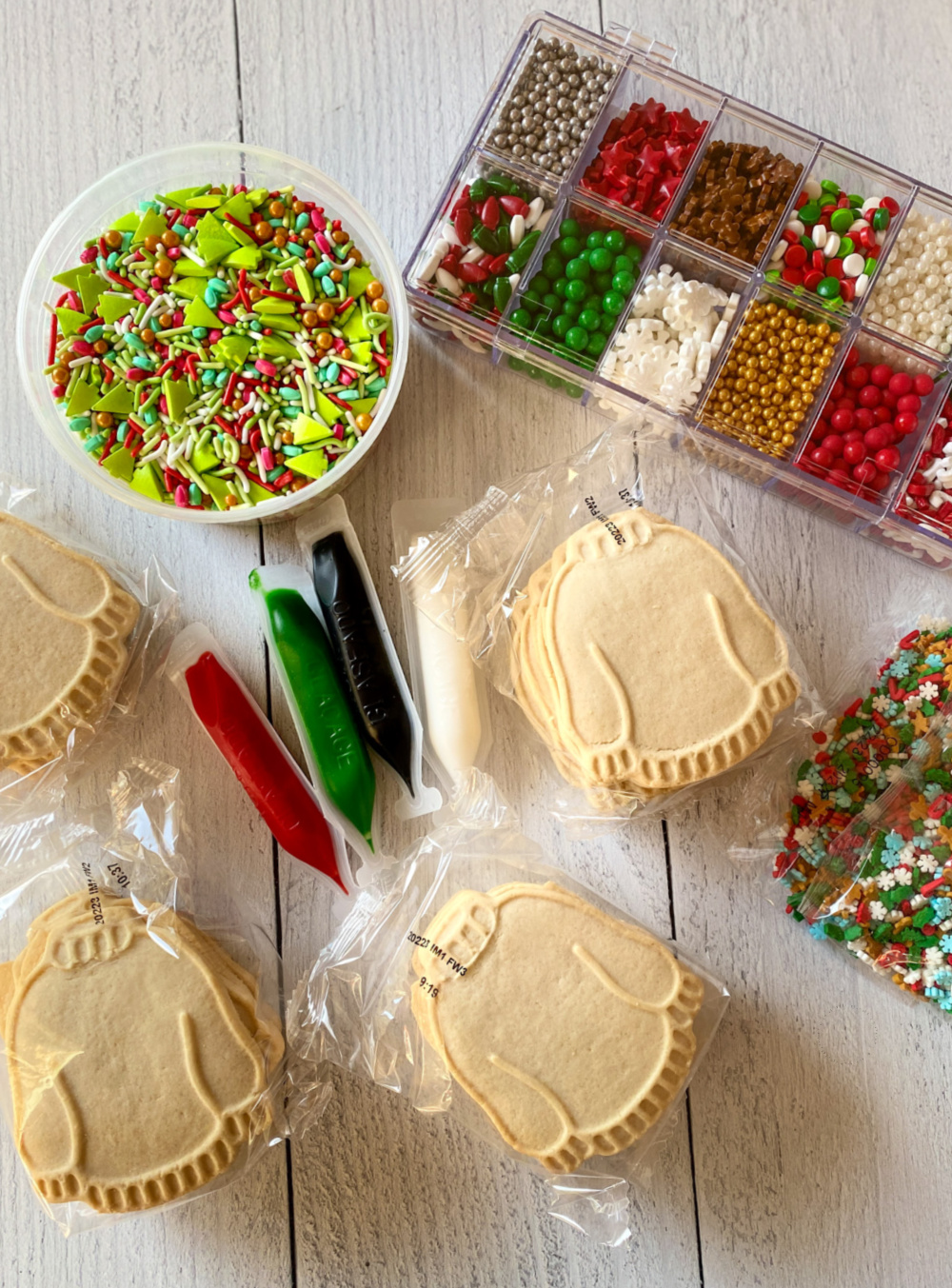 mostrando lo que viene dentro de un kit de galletas. La caja tiene galletas de suéter feo prefabricadas, chispas y glaseado real de colores.