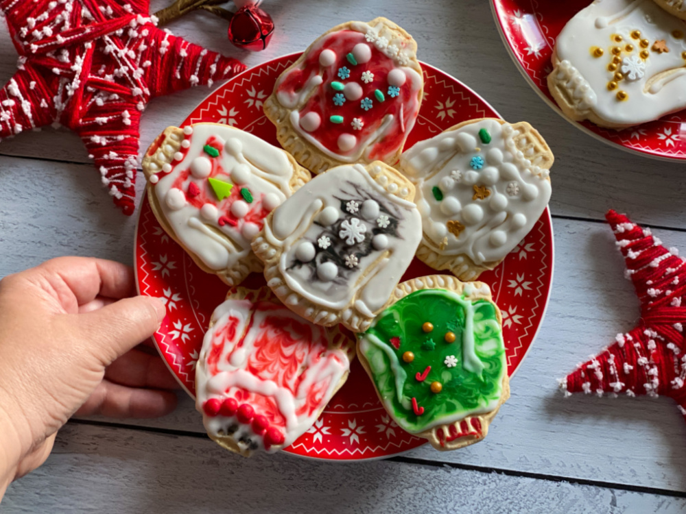 a hand holding a plate of decorated sugar cookies