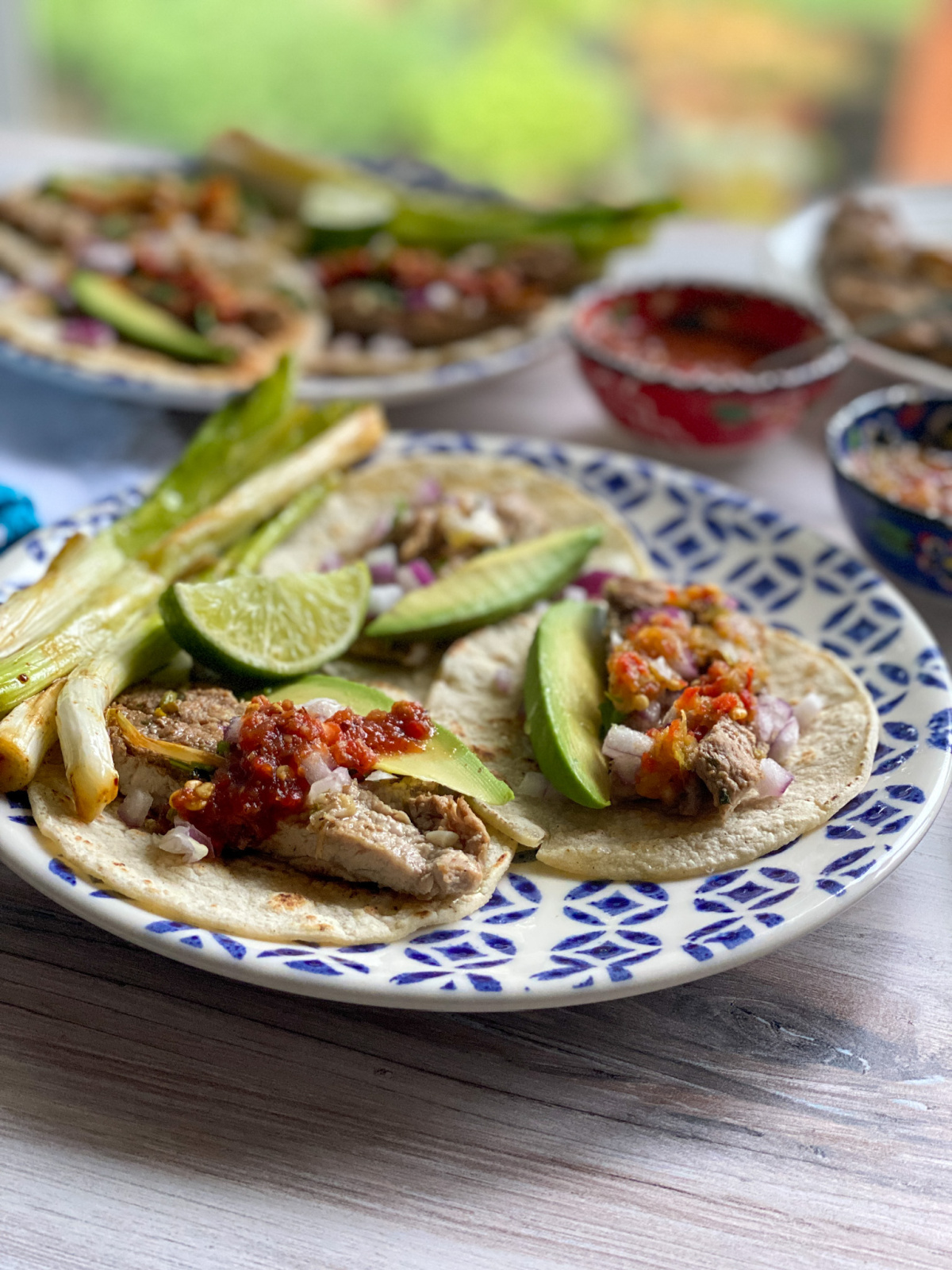 a plate with grilled meat tacos garnished with salsa and avocado