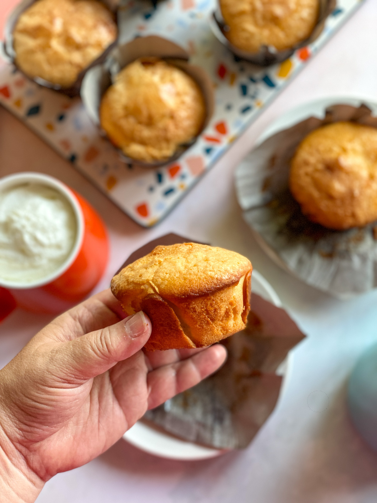 A hand holding a small cake made with fresh orange juice, wheat flour, milk and butter