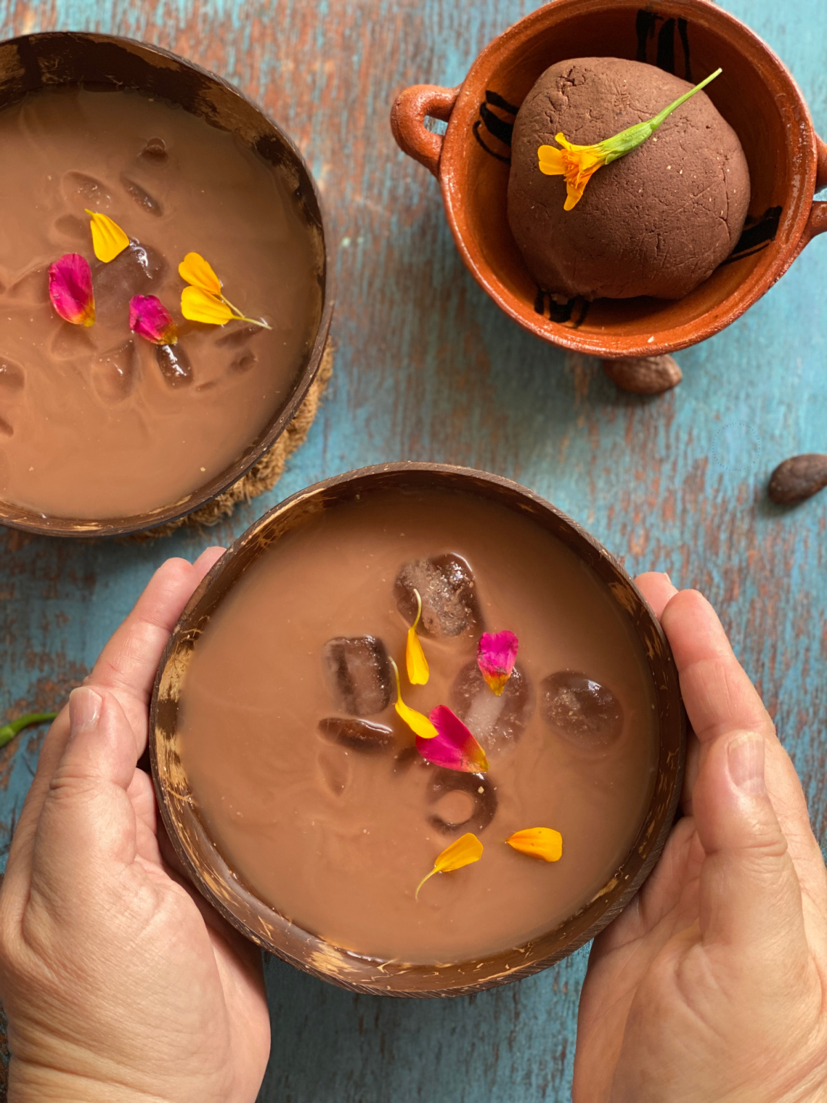 Two hands holding a bowl with a cacao masa harina drink called pozol