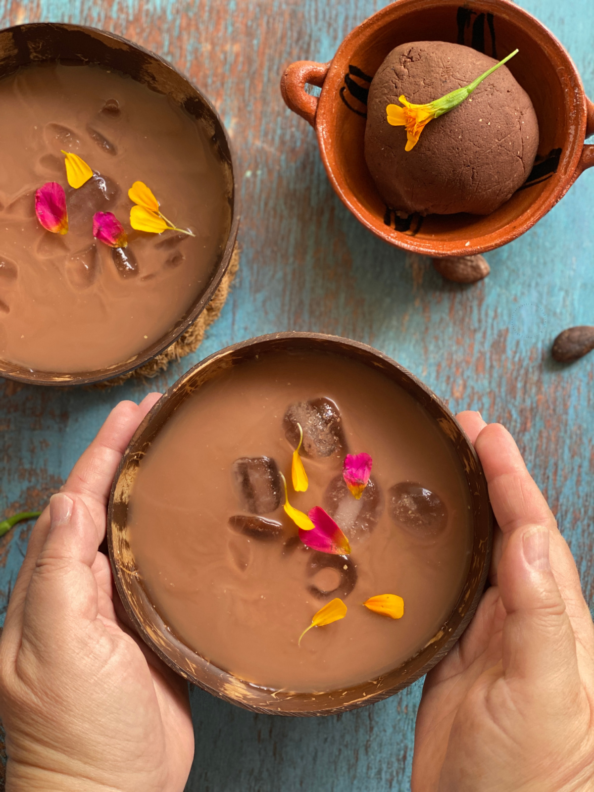 Dos manos sosteniendo un cuenco con una bebida de maíz y cacao llamada pochotl