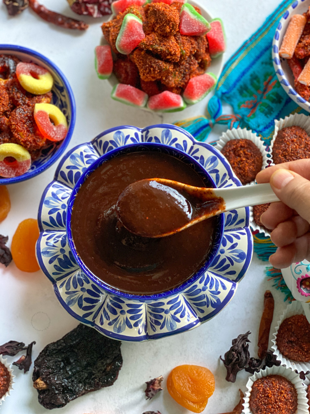 a hand holding a spoon with sauce