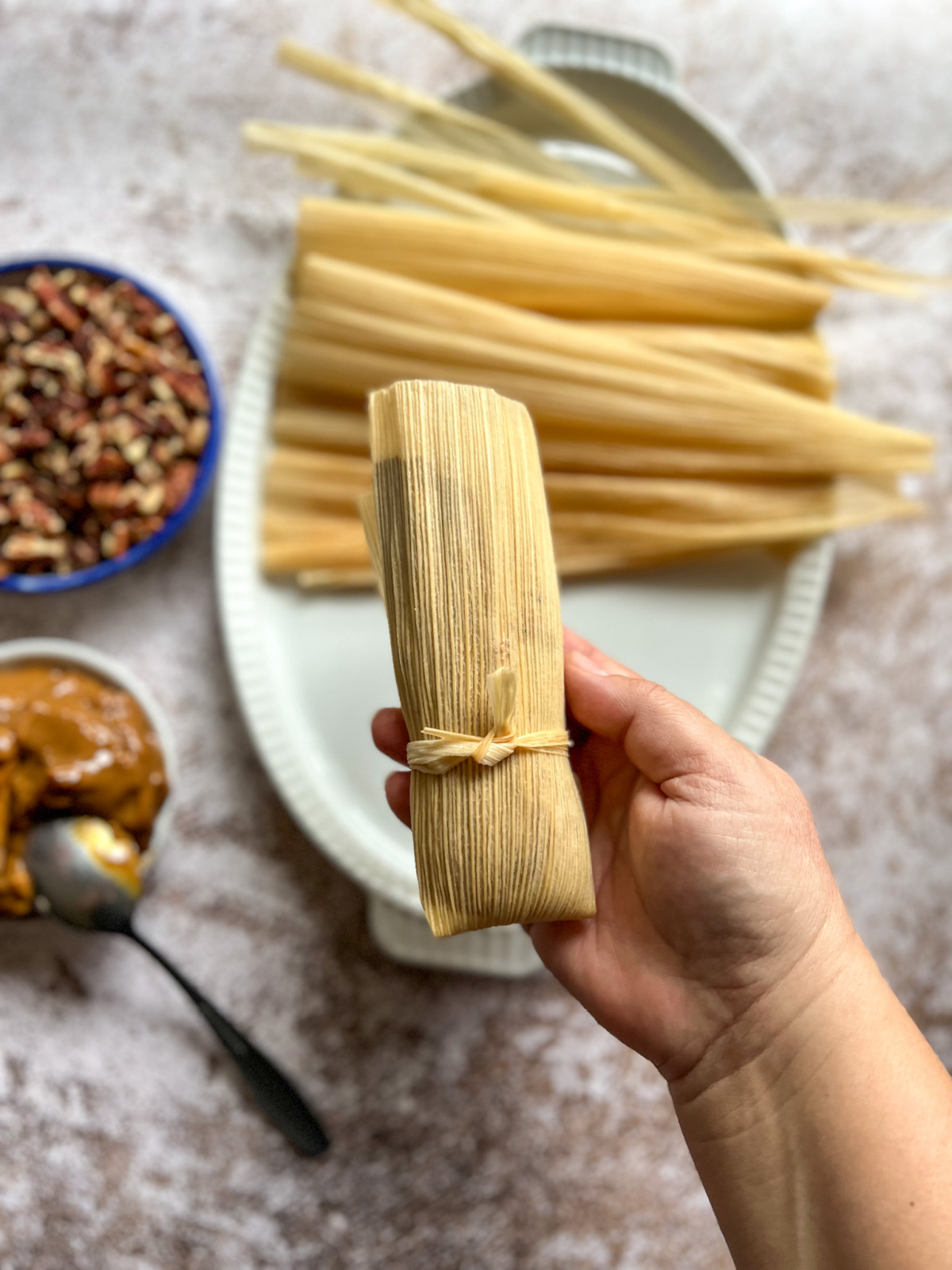 a hand holding a tamal