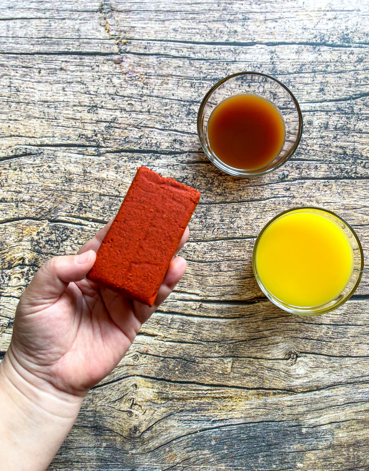 A hand holding a brick of achiote paste