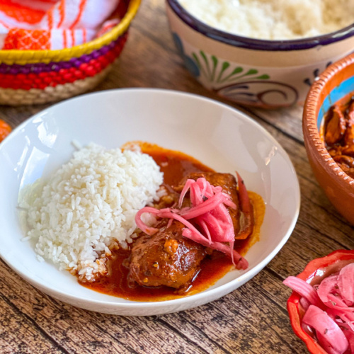 a round plate served with chicken pibil and rice