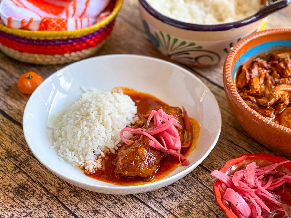a round plate served with chicken pibil and rice