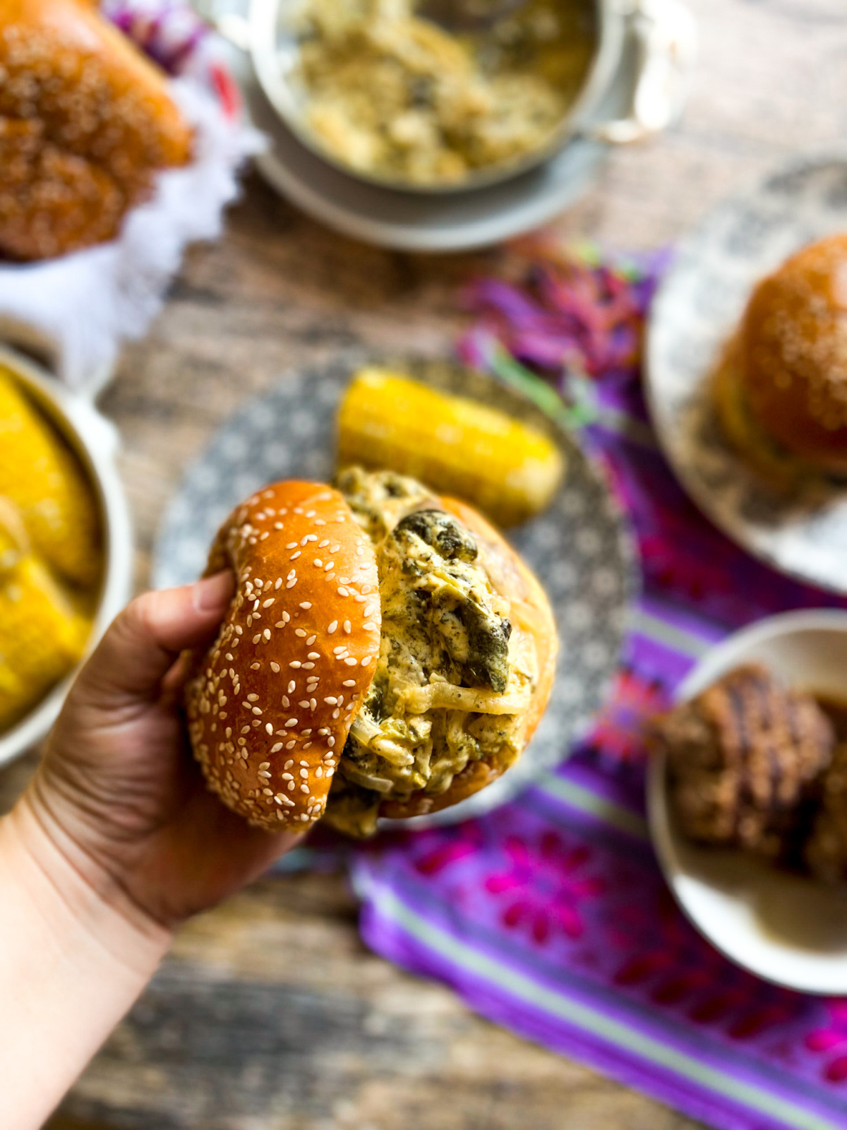 una mano agarrando una hamburguesa estilo mexicano