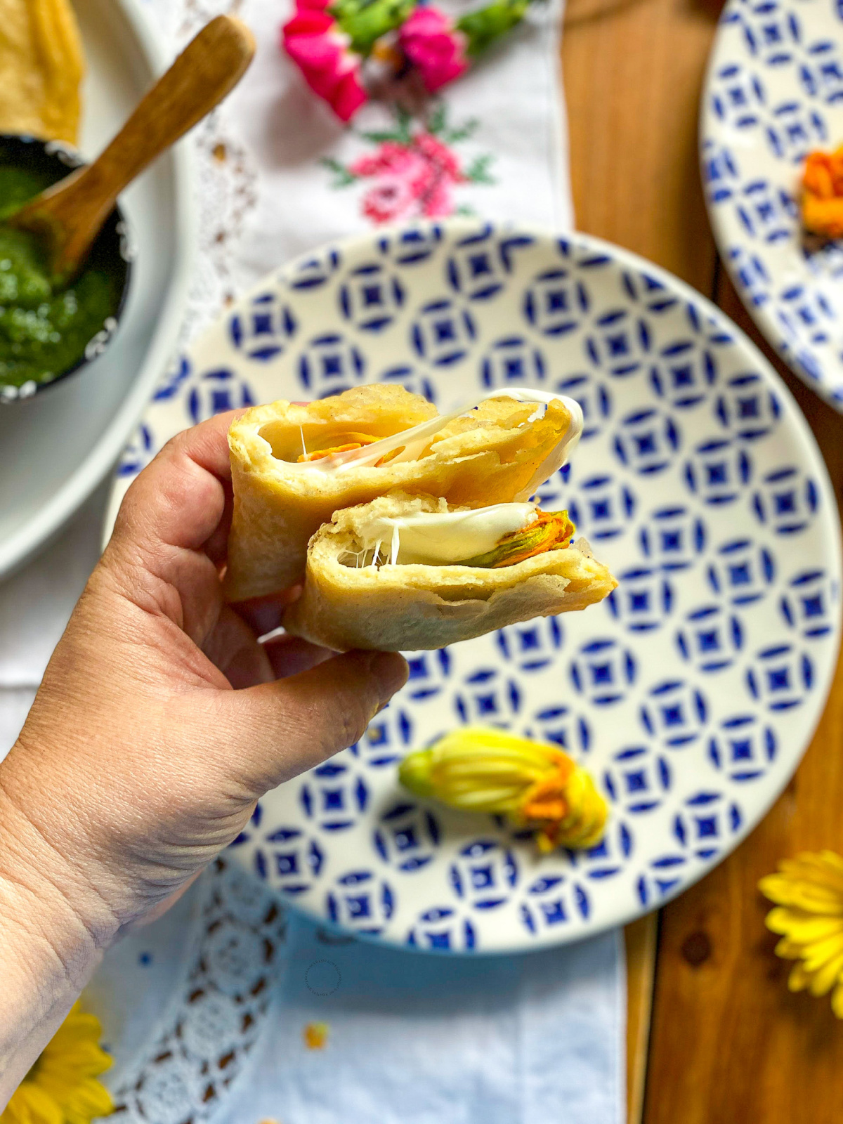 una mano sosteniendo una quesadilla que muestra el queso derretido dentro