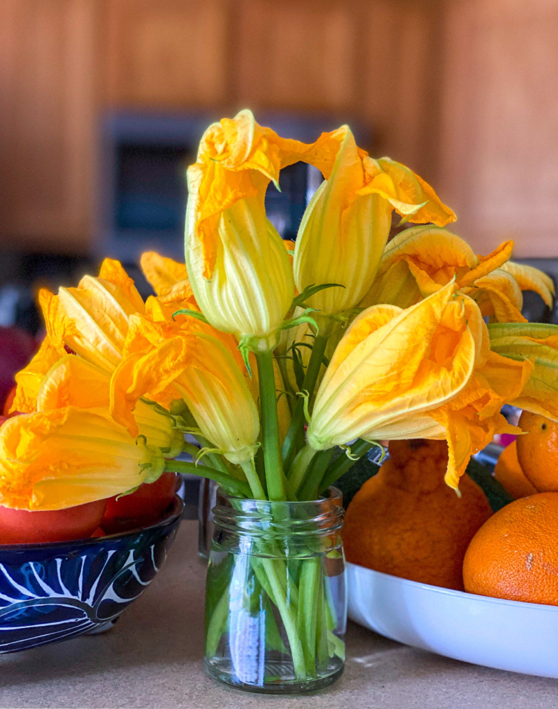 a vase with squash blossoms in water