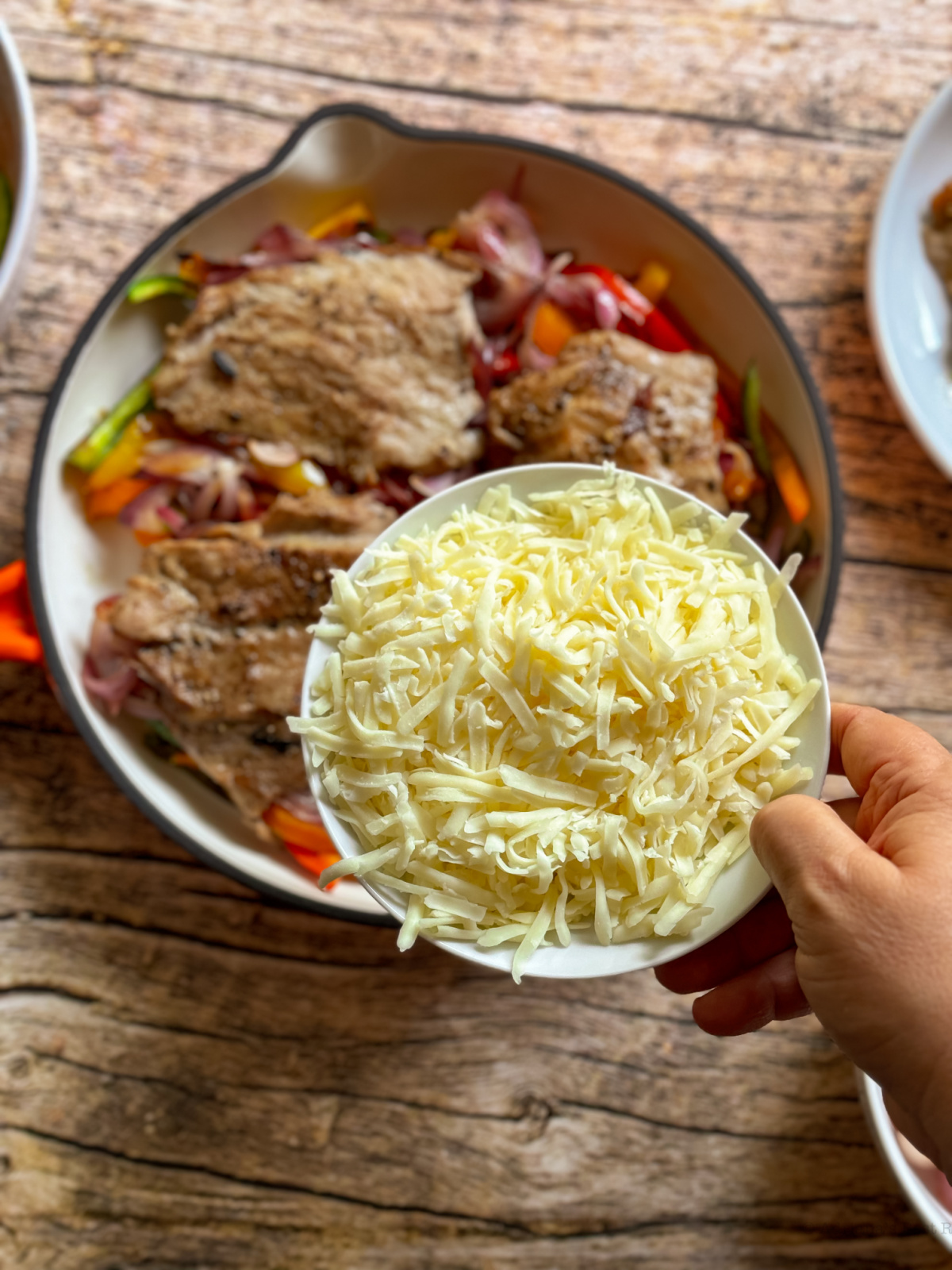 una mano sosteniendo un cuenco con queso rallado